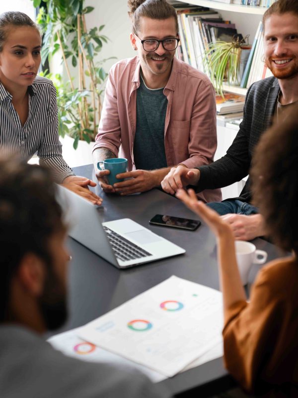 Diverse group of businesspeople discussing charts during a meeting together in a modern office. Startup, financial statistics, teamwork concept